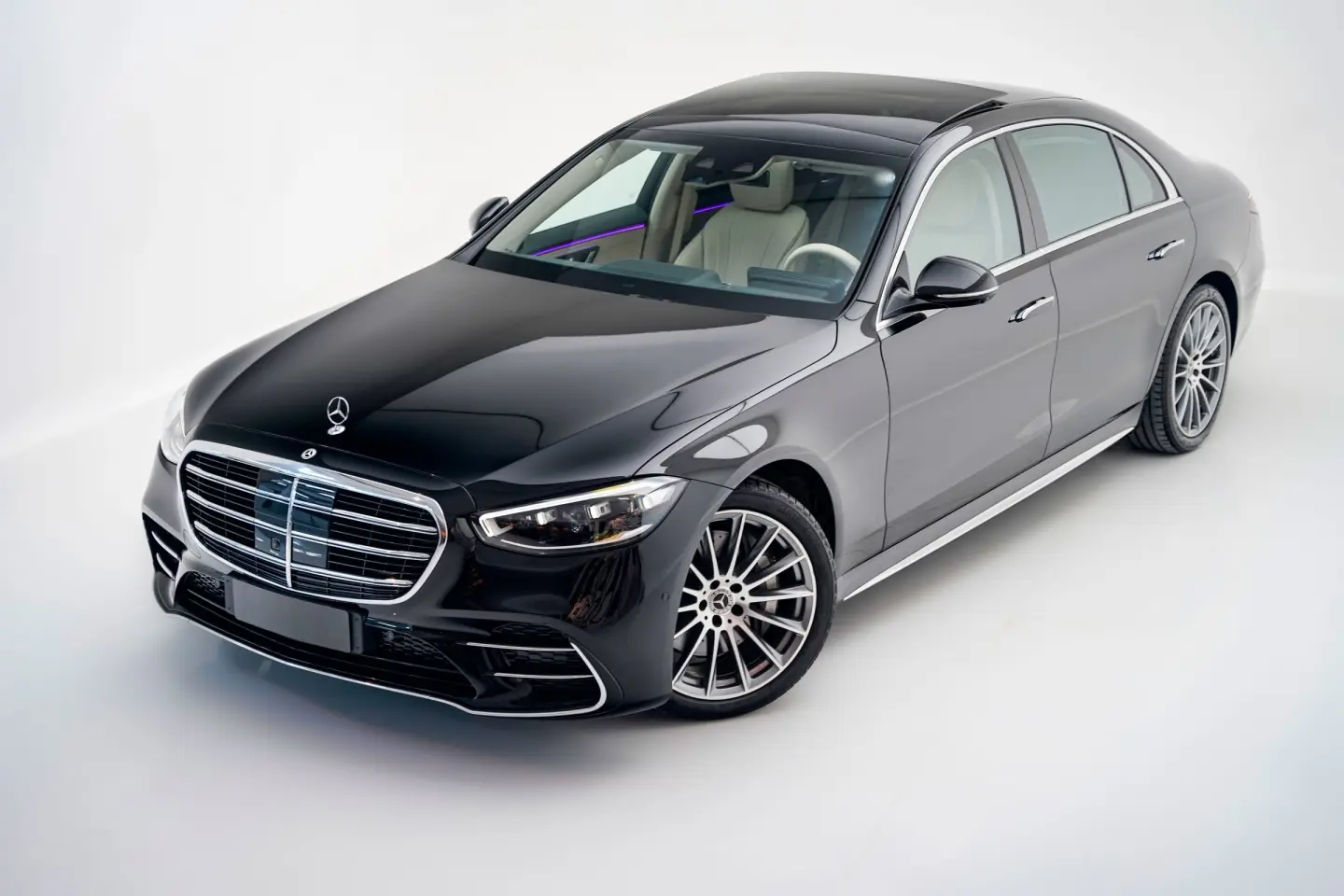 Black Mercedes-Benz S-Class sedan with a cream leather interior, shown in front three-quarter view in a white studio.