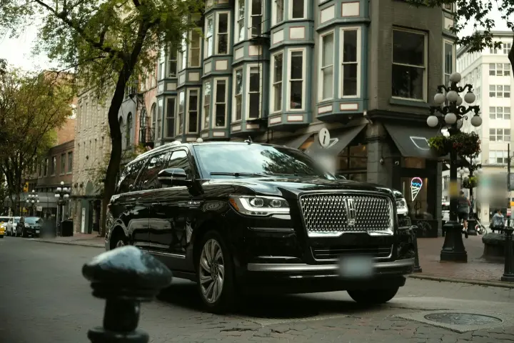 Black Lincoln Navigator full-size SUV parked on a brick-paved street lined with older multi-story buildings.