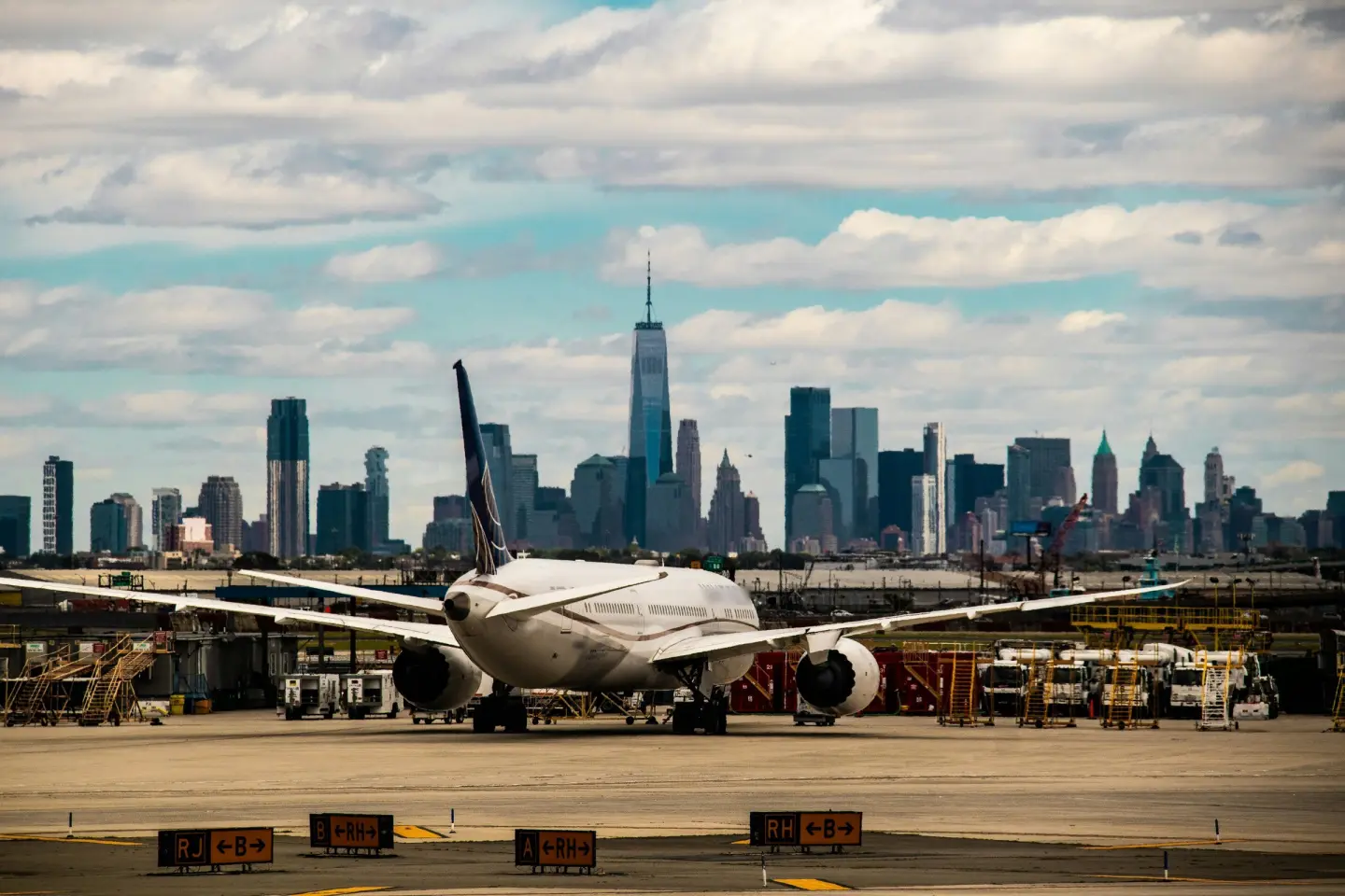 Widebody passenger jet on the apron at Newark Liberty International Airport, with the Lower Manhattan skyline behind.